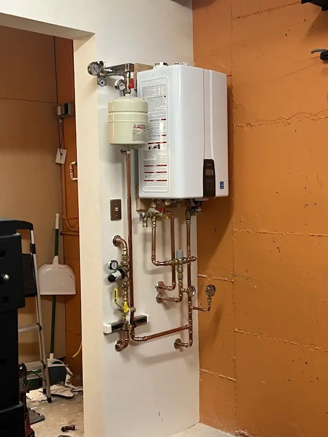 Plumbing technician inspecting water heater connections in Hudson